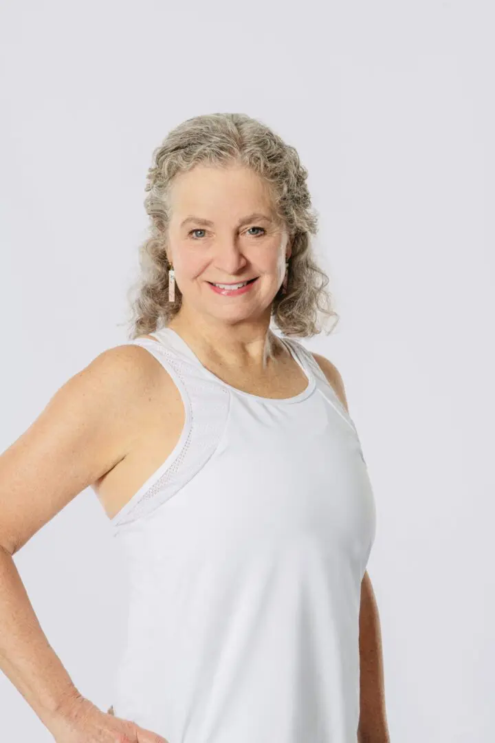 A woman with curly hair wearing white tank top.